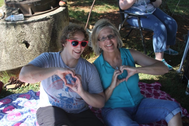 Two ladies making a heart with their hands sitting on a blanket outside of Planned Parenthood.